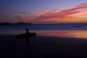 A Lone Surfer walks up the beach at Whitesands Bay St Davids in the fading light of an autumnal susnset