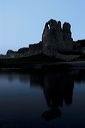 As the light fades at dusk the reflection of the castle at Ogmore appears in the river.