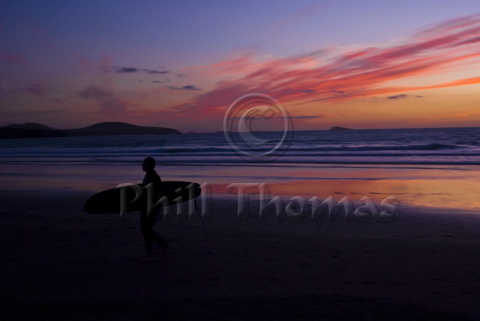 A Lone Surfer walks up the beach at Whitesands Bay St Davids in the fading light of an autumnal susnset
