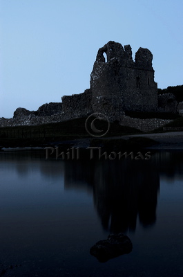 As the light fades at dusk the reflection of the castle at Ogmore appears in the river.
