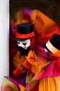 Two people in clown costumes appearing to share a joke at the carnival of the mask in Venice