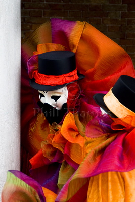 Two people in clown costumes appearing to share a joke at the carnival of the mask in Venice